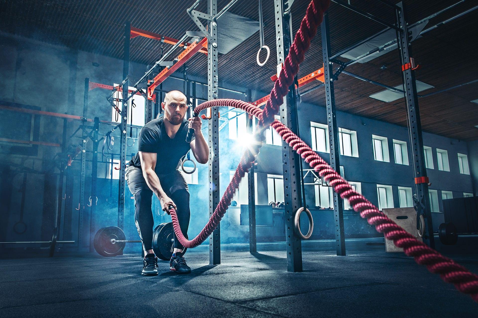 Athlete training with red battle ropes in a dramatic gym